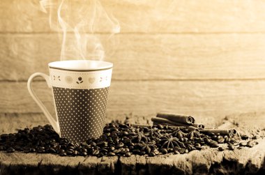 Kahve fincanı ve ahşap masa üzerinde etrafında kahve çekirdekleri