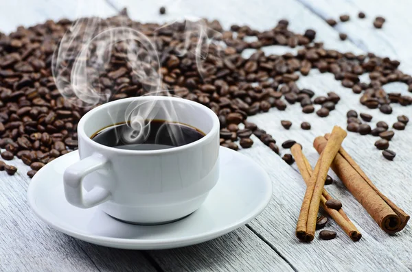 Taza de café blanco con humo y granos de café alrededor — Foto de Stock