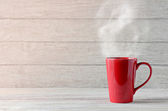 červený šálek kávy na dřevěném stole