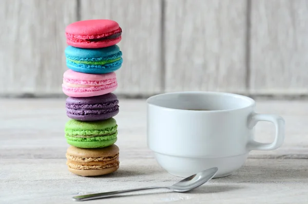 Taza de café blanco y pila de macaron en mesa de madera — Foto de Stock