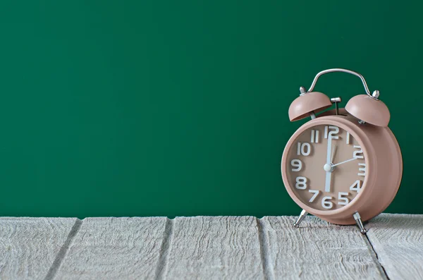 Bruin klok op houten tafel met groene achtergrond — Stockfoto