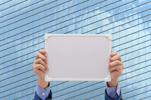 business man hand holding white board with modern building background