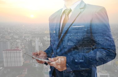 Double exposure of business man using tablet over the city