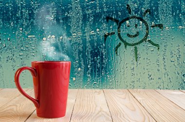 red coffee cup with smoke and sun sign on water drops glass wind