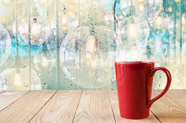 Rode koffiekopje met natuurlijke waterdruppels op venster — Stockfoto