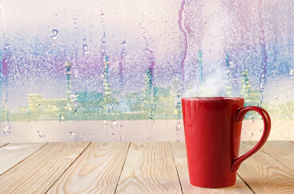 Rote Kaffeetasse mit natürlichen Wassertropfen auf Glasfensterhintergrund — Stockfoto