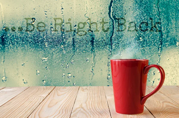 Red coffee cup with smoke on water drops glass window background — Stock Photo, Image