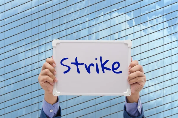 Uomo d'affari mano tenendo bordo bianco con il testo "Strike " — Foto Stock