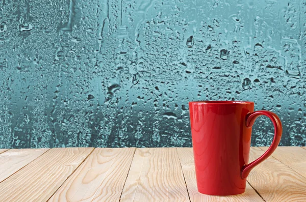 Rode koffiekopje met natuurlijke water druppels op glazen venster achtergrond — Stockfoto