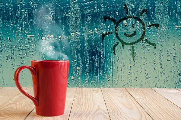 Red coffee cup with smoke and sun sign on water drops glass wind — Stock Photo, Image