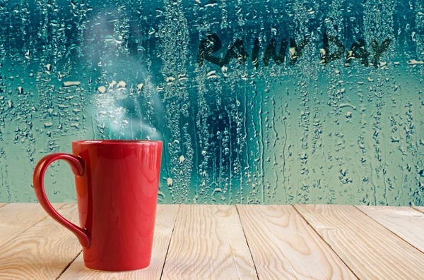 Kırmızı kahve fincanı su duman ile cam pencere adam damla