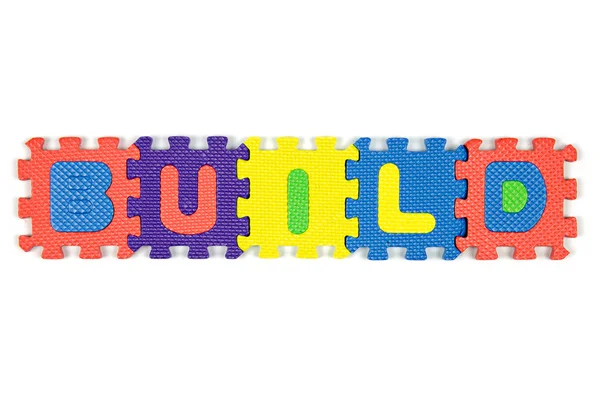 Color alphabet jigsaw on white background in word "Build" — Stock Photo, Image