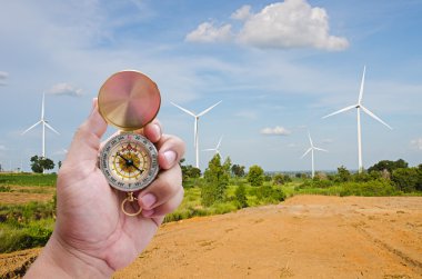 Man hand and compass with wind turbine field background clipart