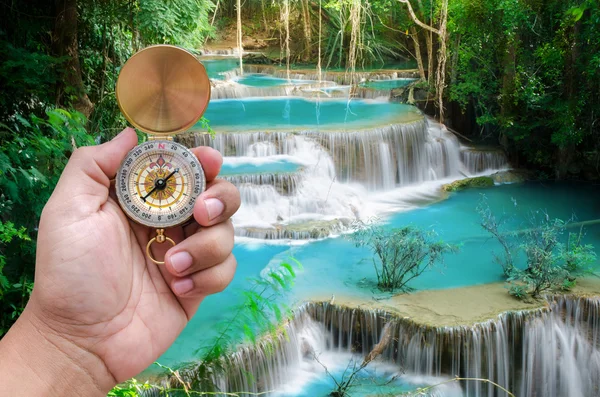 Man hand and compass with beautiful deep forest waterfall backgr — Stock Photo, Image