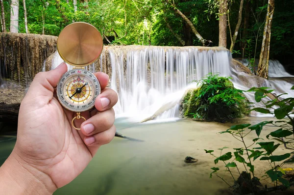 Man hand and compass with beautiful deep forest waterfall backgr — Stock Photo, Image