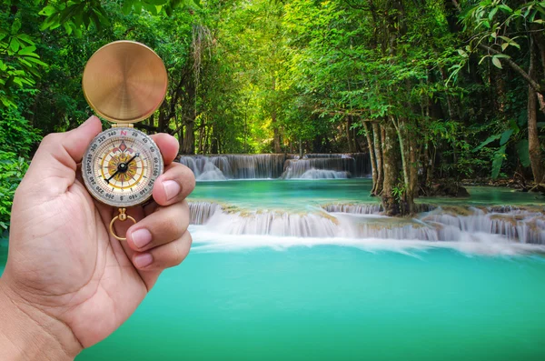 Man hand and compass with beautiful deep forest waterfall backgr — Stock Photo, Image