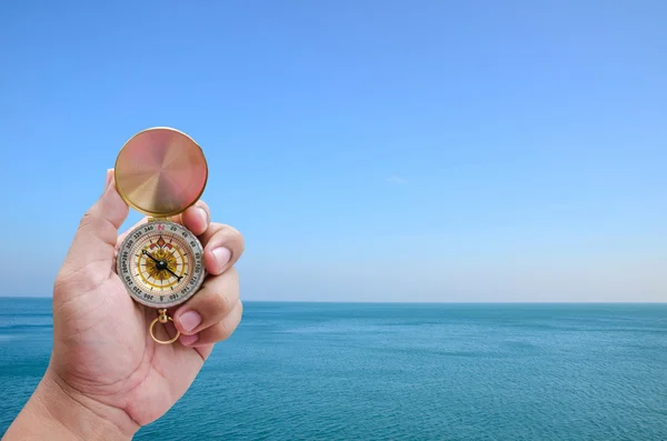 Mão de homem e bússola sobre visão de ângulo largo na paisagem marinha — Fotografia de Stock