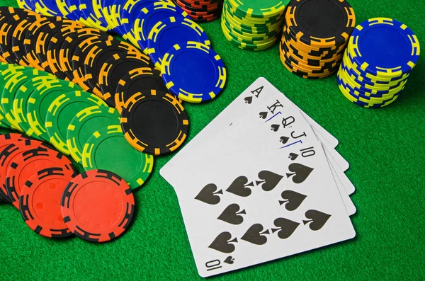 Playing cards 'royal flush' and chips on green background — Stock Photo, Image