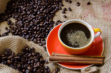 Turuncu kahve fincanı ve kahve çekirdekleri çevresinde