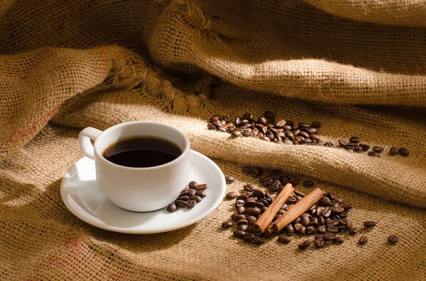 Coffee cup and coffee beans around — Stock Photo, Image