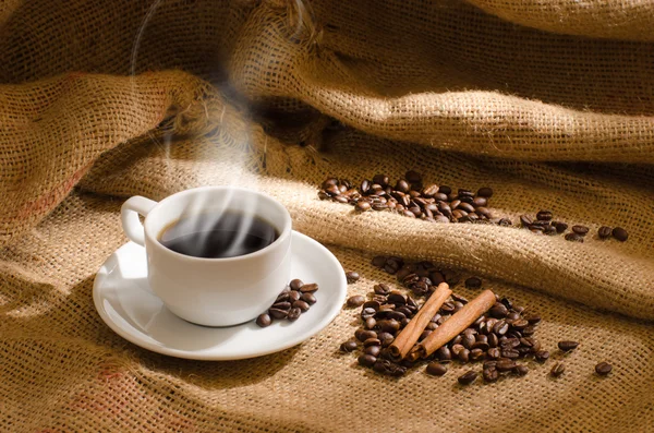 Tasse à café blanche avec fumée et grains de café autour — Photo