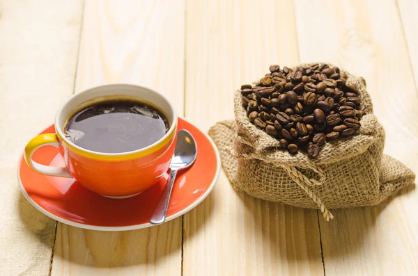 Tasse à café et café rôti en sac sur table en bois — Photo