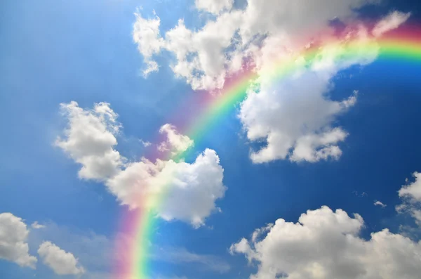 Arco-íris e nuvens brancas em fundo céu azul — Fotografia de Stock