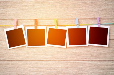 clothespins ile ahşap arkasında asılı boş siyah fotoğraf çerçeveleri
