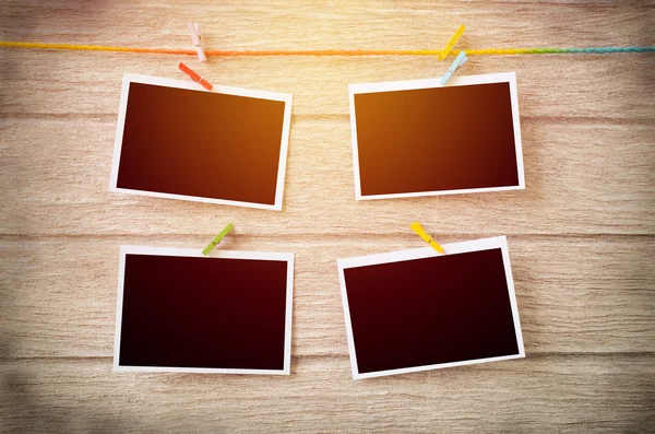 Empty black photo frames hanging with clothespins on wooden back — Stock Photo, Image