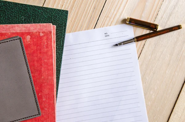 Stift auf leerem Papier mit Stapel alter Bücher — Stockfoto