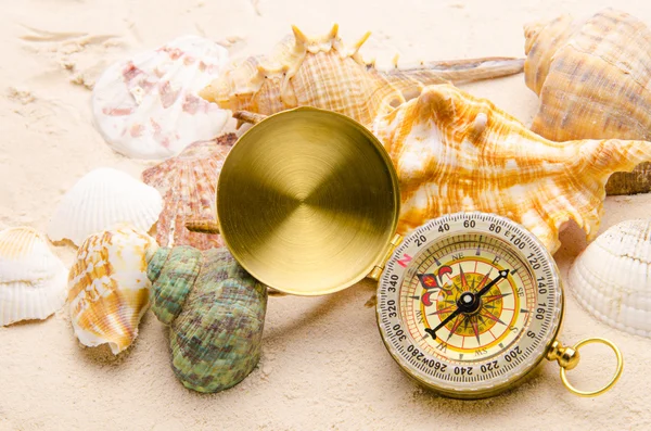 Kompas en zee schelpen op zand — Stockfoto