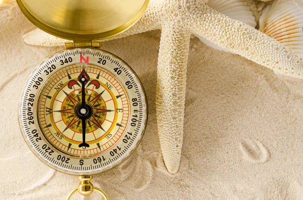 Compass and sea shells on sand — Stock Photo, Image