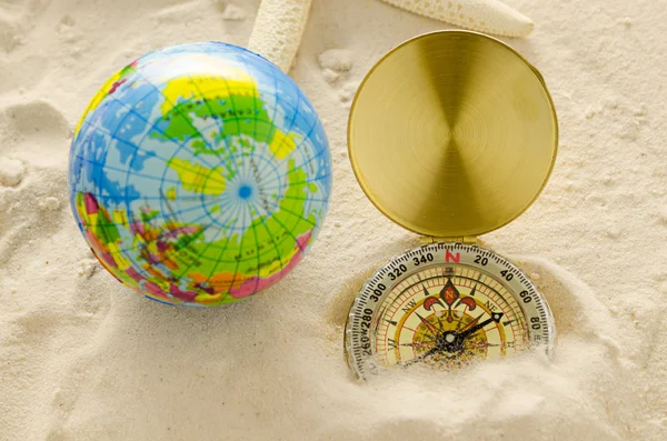 Compass and world model on sea sand — Stock Photo, Image