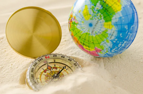 Compass and world model on sea sand — Stock Photo, Image