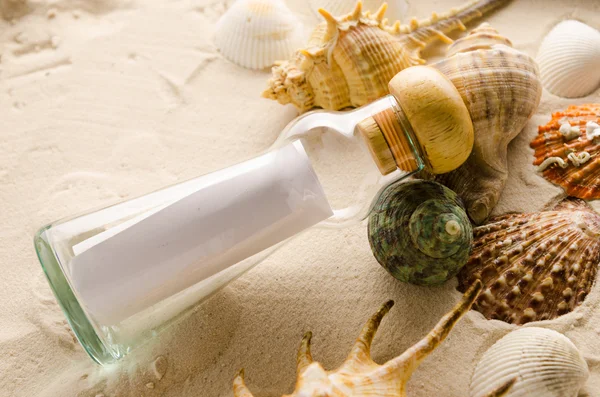 Carta garrafa e conchas do mar no fundo de areia — Fotografia de Stock