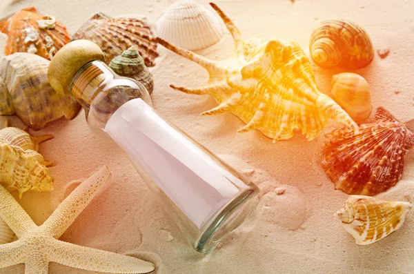 Bottle letter and sea shells on sand background — Stock Photo, Image