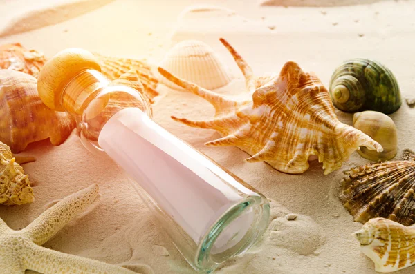 Bottle letter and sea shells on sand background — Stock Photo, Image