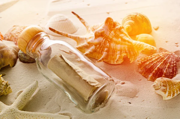 Bottle letter and sea shells on sand background — Stock Photo, Image