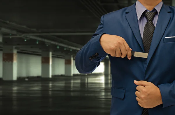 Бизнесмен держит нож на фоне опасной зоны — стоковое фото
