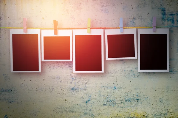 Empty black photo frames hanging with clothespins on stone wall — Stock Photo, Image