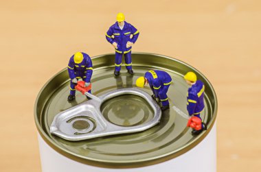 Miniature workmen team trying to open food can lid clipart