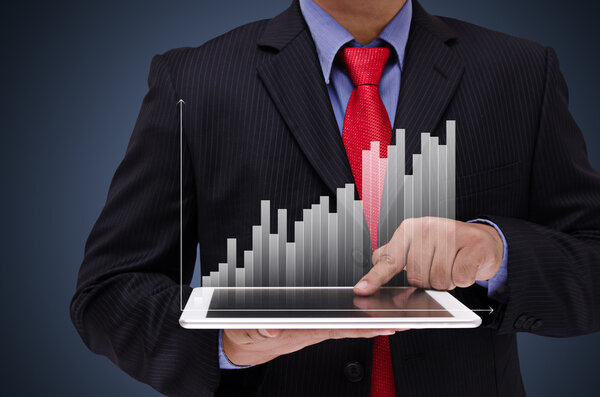 business man holding tablet with business graph virtual screen