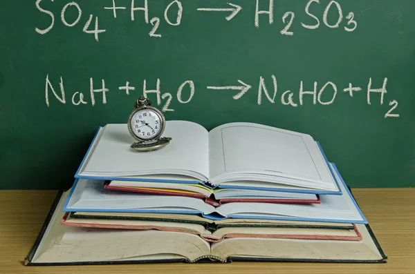 Pendent clock on stack of open book — Stock Photo, Image