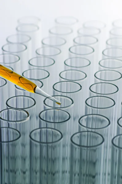 Pipette de laboratoire scientifique avec goutte sur fond de tube à essai, l — Photo