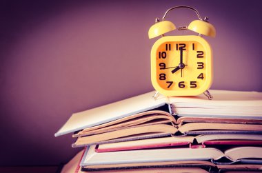 çalar saat açık kitap yığını üzerinde