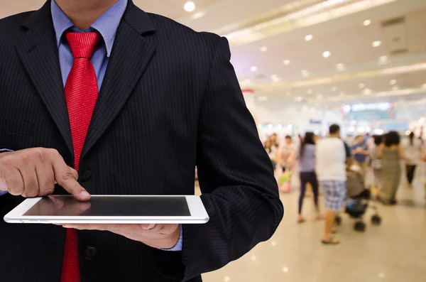 Geschäftsmann hält Tablet mit verschwommenem Ereignishintergrund — Stockfoto