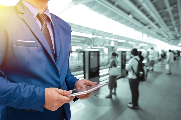 Geschäftsmann hält Tablet mit verschwommenem Bahnhof-Hintergrund — Stockfoto