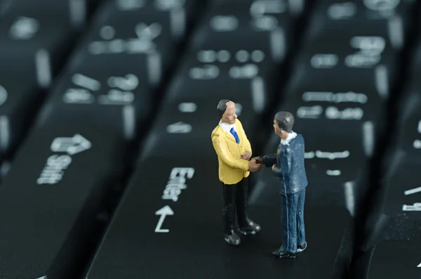 Miniature people shake hand on keyboard backgroud — Stock Photo, Image