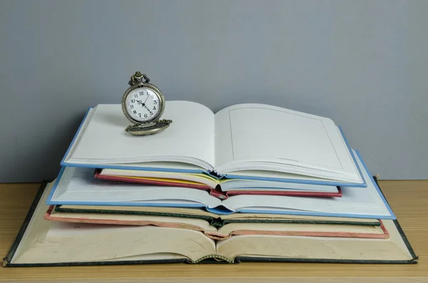 Hängende Uhr auf Stapel mit offenen Büchern — Stockfoto