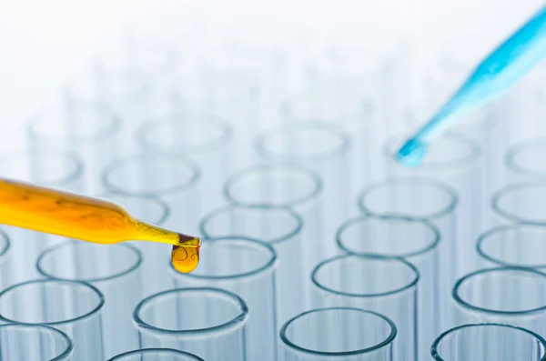 Science laboratory pipette with drop on test tube background — Stock Photo, Image